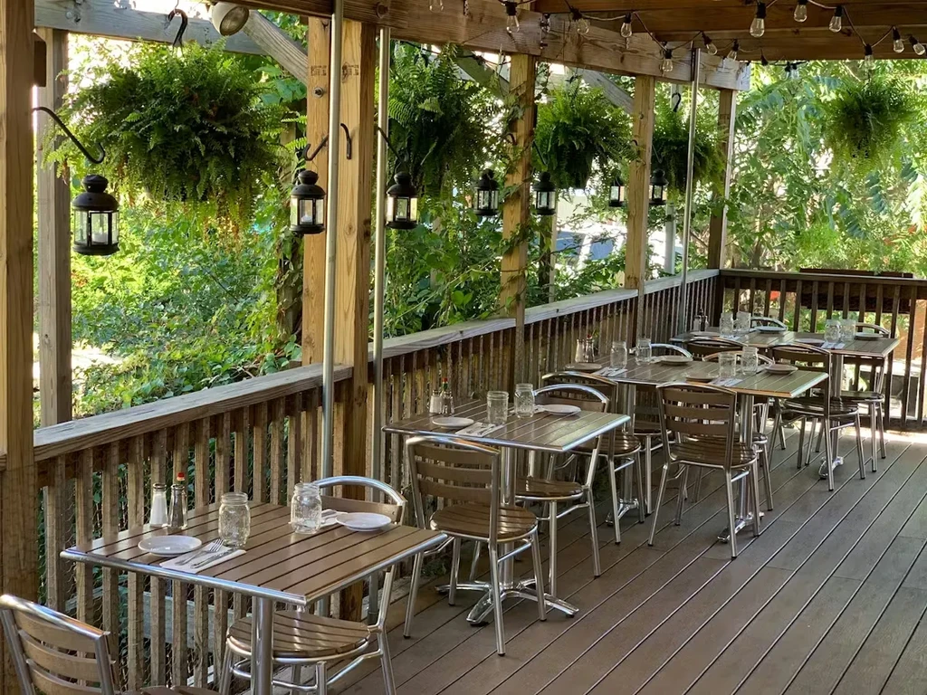 Empty outdoor restaurant patio with set tables under a wooden pergola.