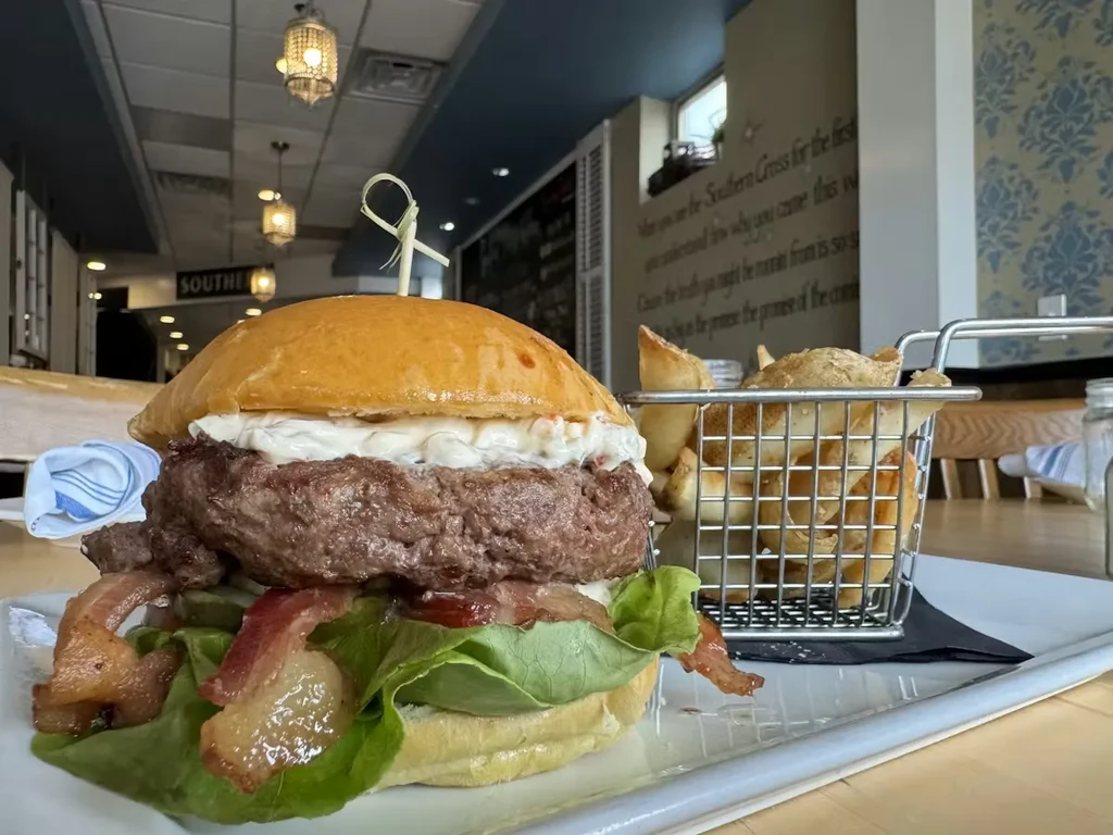 Close-up: a burger with bacon, fries, and lettuce in a restaurant.