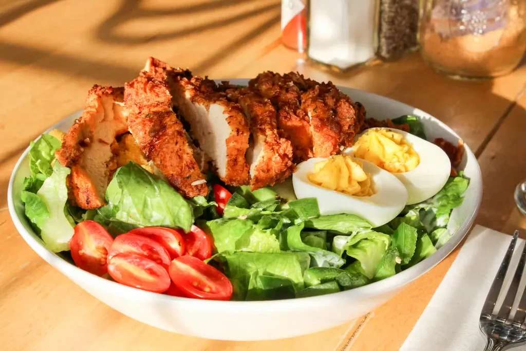Fried chicken salad with hard-boiled eggs, tomatoes, and lettuce.
