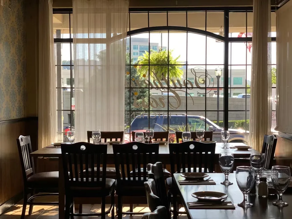 Empty restaurant interior with window text, set tables, and street view.