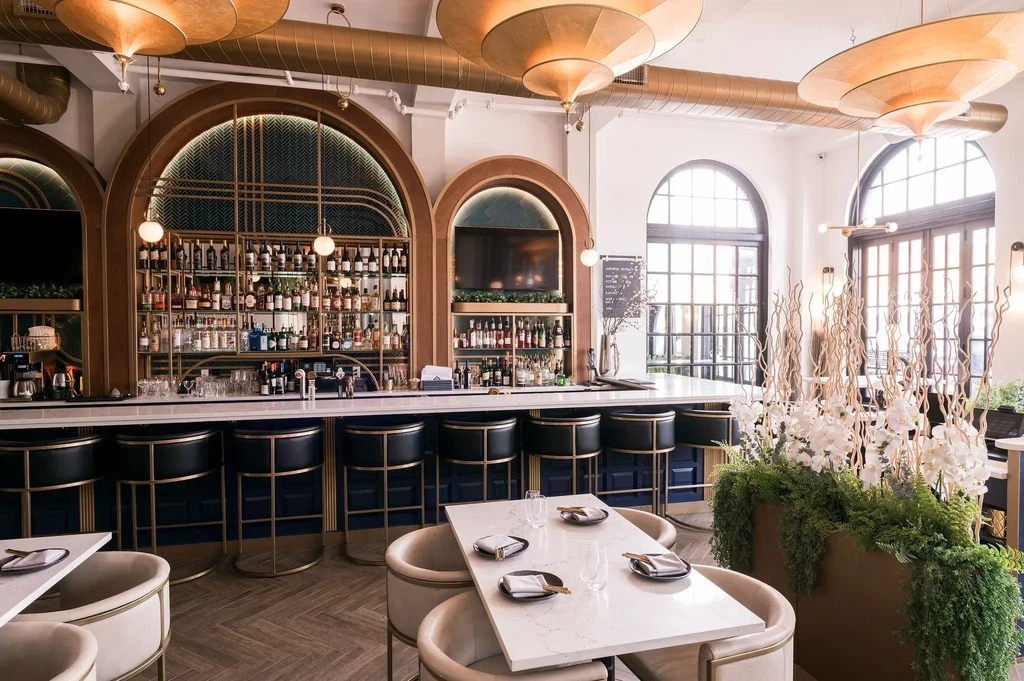Elegant, empty restaurant with a stylish, well-stocked bar and gold accents.