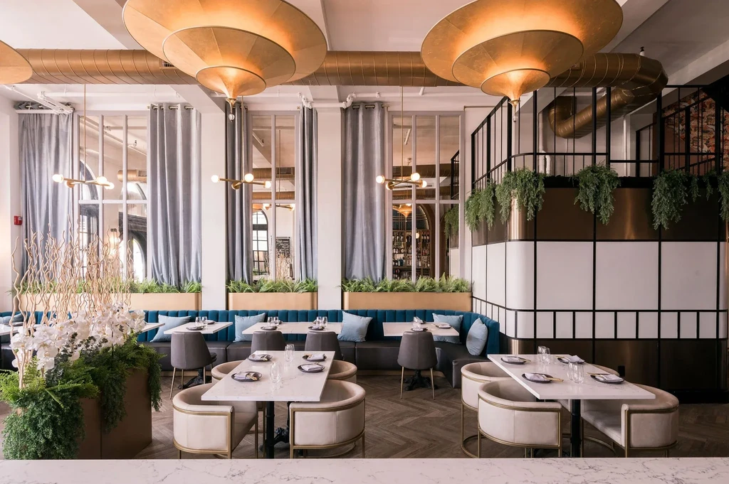 Empty, upscale restaurant with velvet banquette, marble tables, gold fixtures.