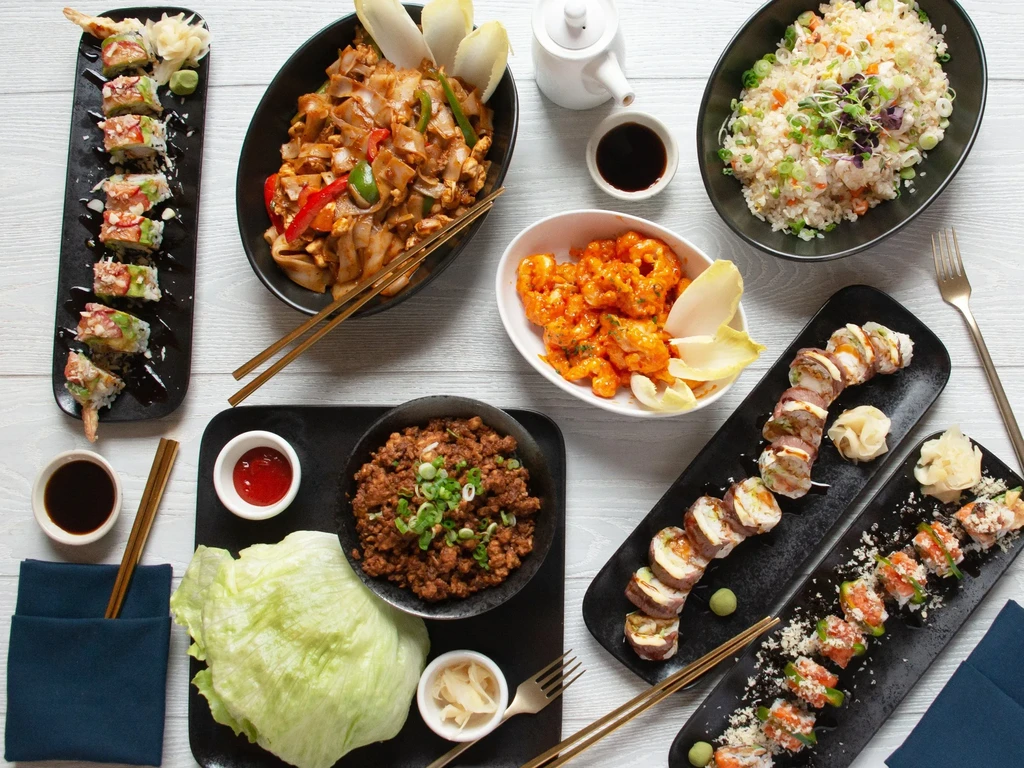 Overhead view: diverse Asian dishes including sushi, noodles, fried rice, shrimp.