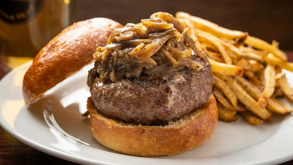 Burger with caramelized onions, melted cheese, and golden fries.