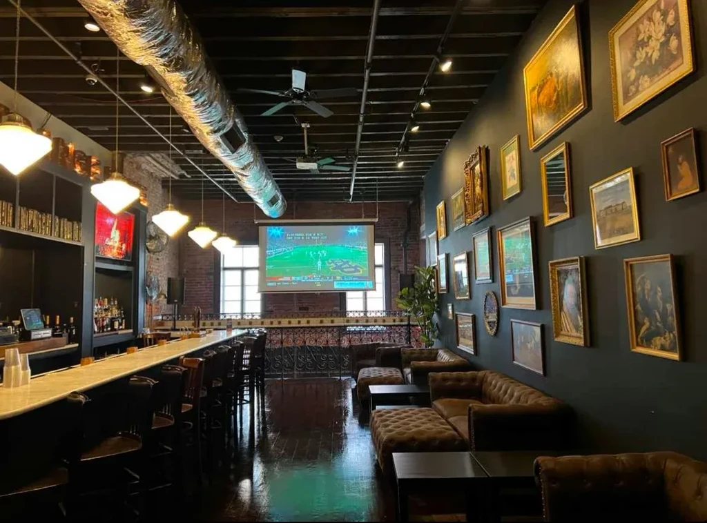 Wide view of a modern industrial bar with lounge and art gallery.