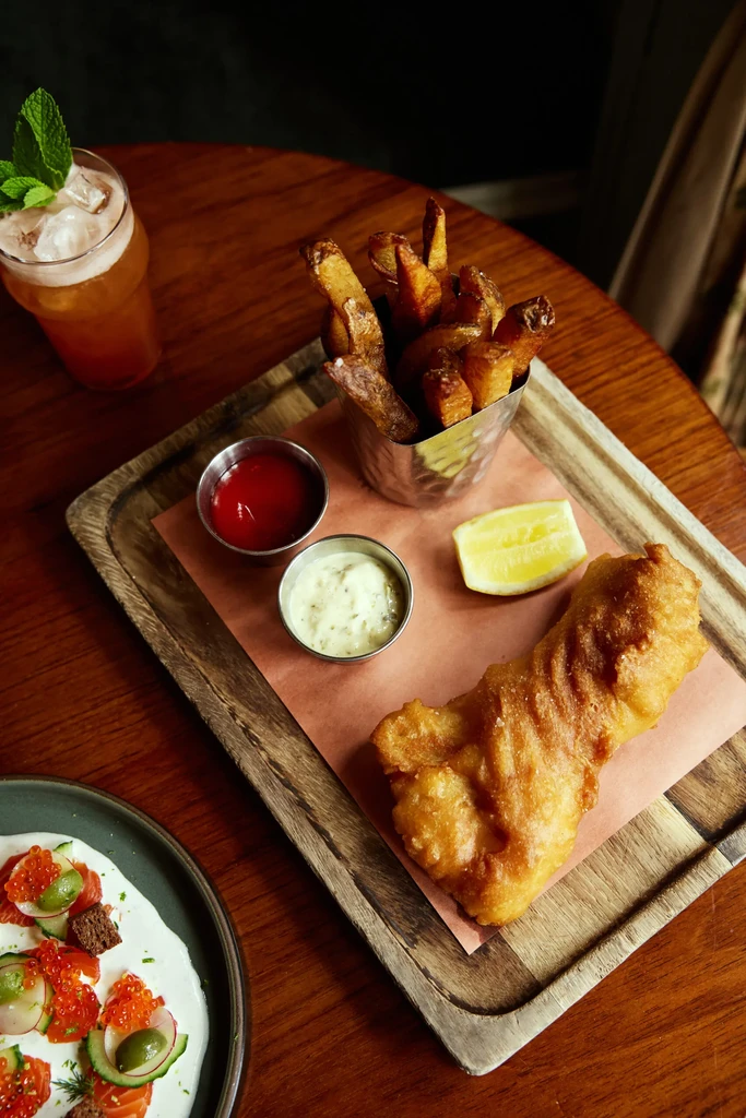 Overhead view of fish and chips, iced drink, and caviar dish.