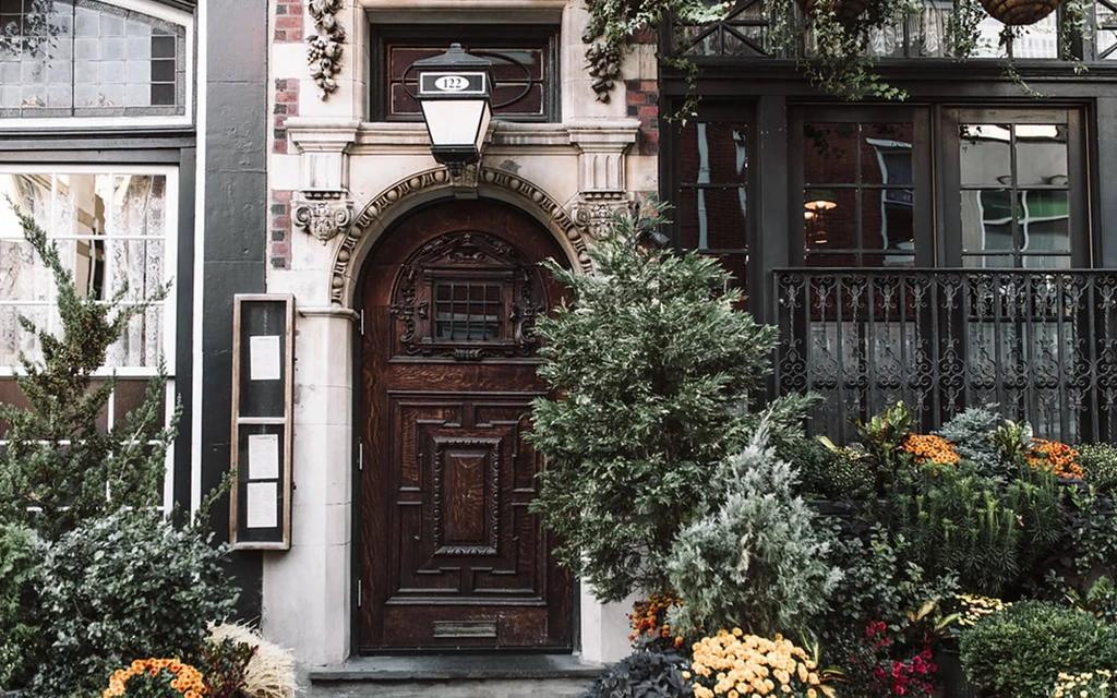 Ornate carved wooden arched door, building exterior with menu and plants.