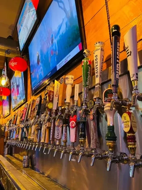 A lively sports bar with many beer taps and TVs showing a game.