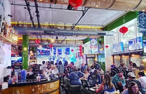 Crowded, stylized sports bar with patrons, a bar, and multiple TVs.