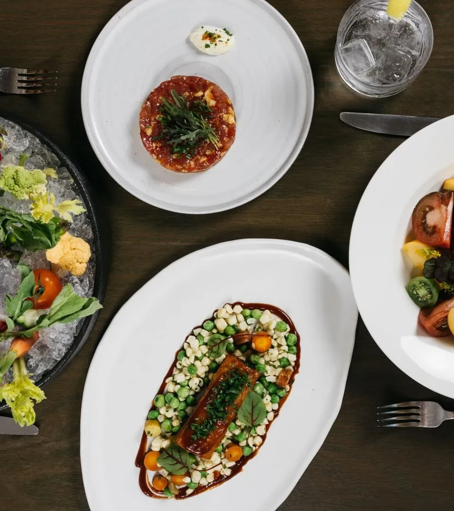 Top-down view of gourmet dishes and a drink on a sophisticated dining table.