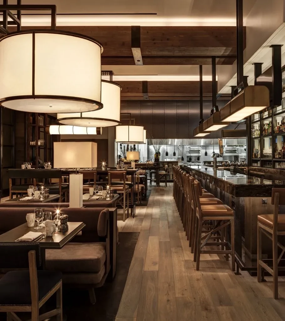 Warmly lit restaurant interior with booths, bar, and open kitchen.