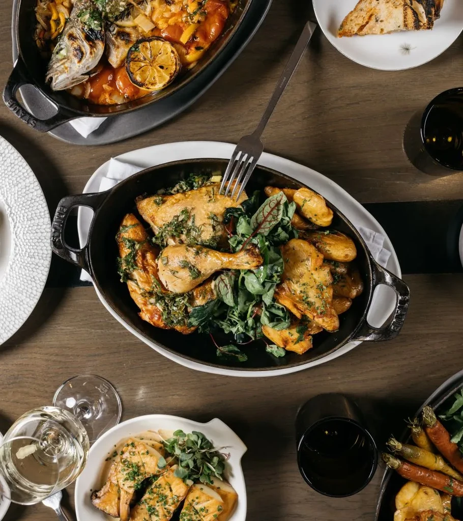 Overhead view of a restaurant table with chicken, fish, and vegetables.