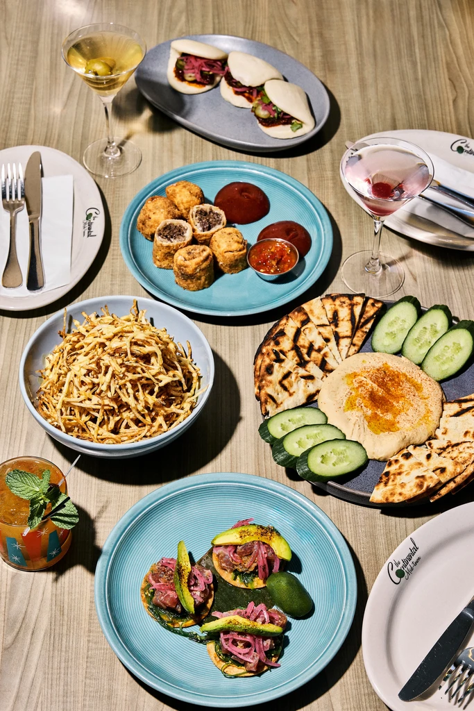 Overhead view of a table featuring diverse, artfully presented food and cocktails.