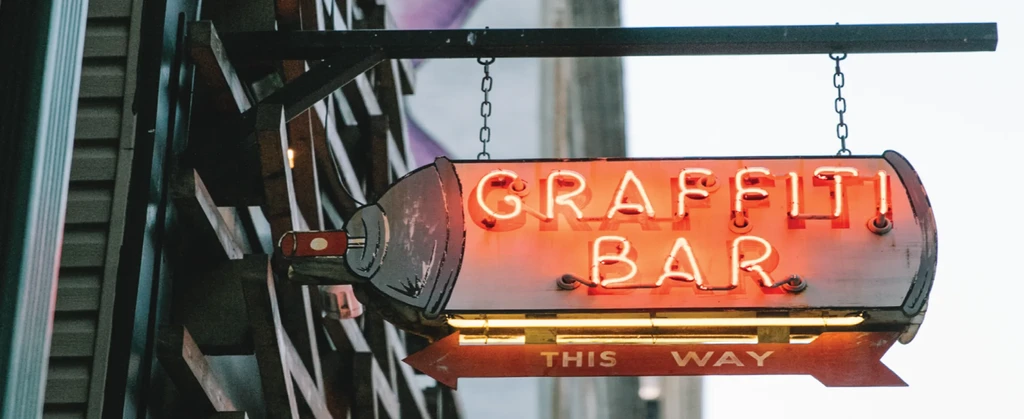 Stylized orange neon 'GRAFFITI BAR' sign with a 'THIS WAY' arrow.