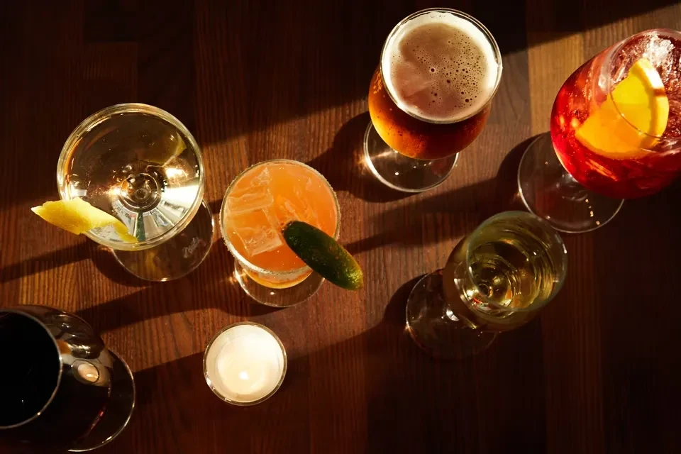Overhead: various drinks, lit candle on dark wood with dramatic lighting.