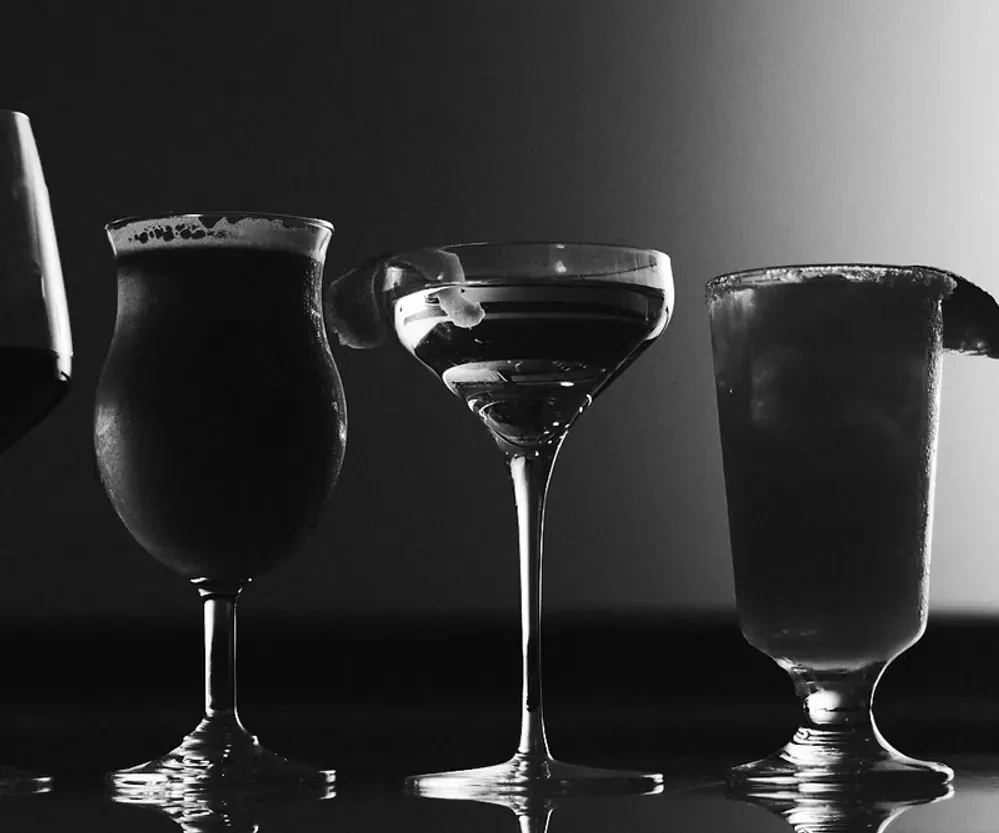 Black and white photo of four backlit drink glasses in silhouette.