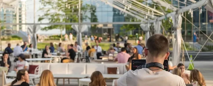 Vibrant urban outdoor gathering with DJ and many seated guests.