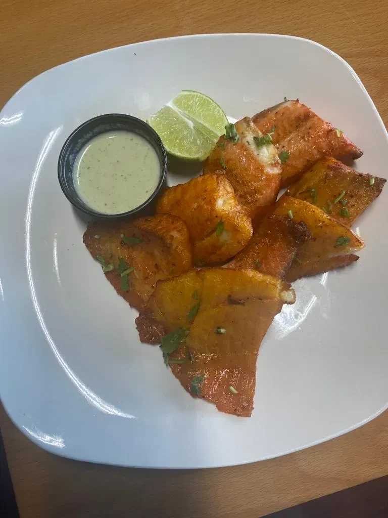 Golden-brown herbed fish or chicken, green dipping sauce, and lime.