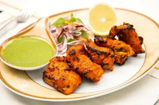 Grilled chicken tikka with charring, green chutney, red onions, and lemon.