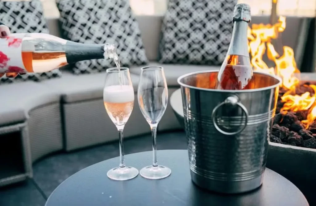 Rosé sparkling wine poured on an outdoor patio with a fire pit.