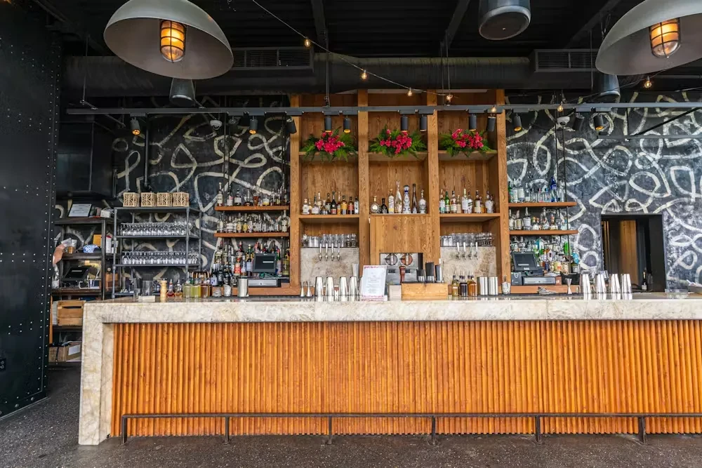Modern restaurant bar with extensive liquor collection and industrial decor.
