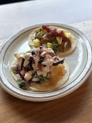 Colorful fish and meat tacos with various toppings on a wooden table.