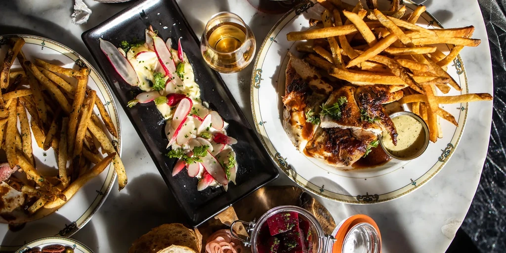 Overhead: Restaurant table with chicken, fries, creamy dish, bread, and drink.