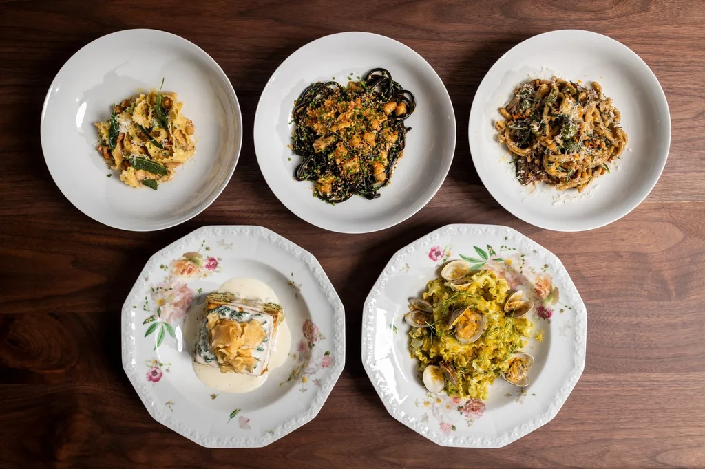 Top-down view: Five distinct pasta dishes on white plates.