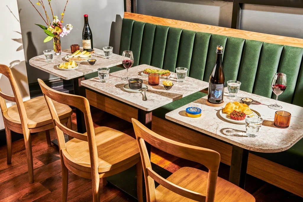 Restaurant interior with three tables set with food, drinks, and flowers.