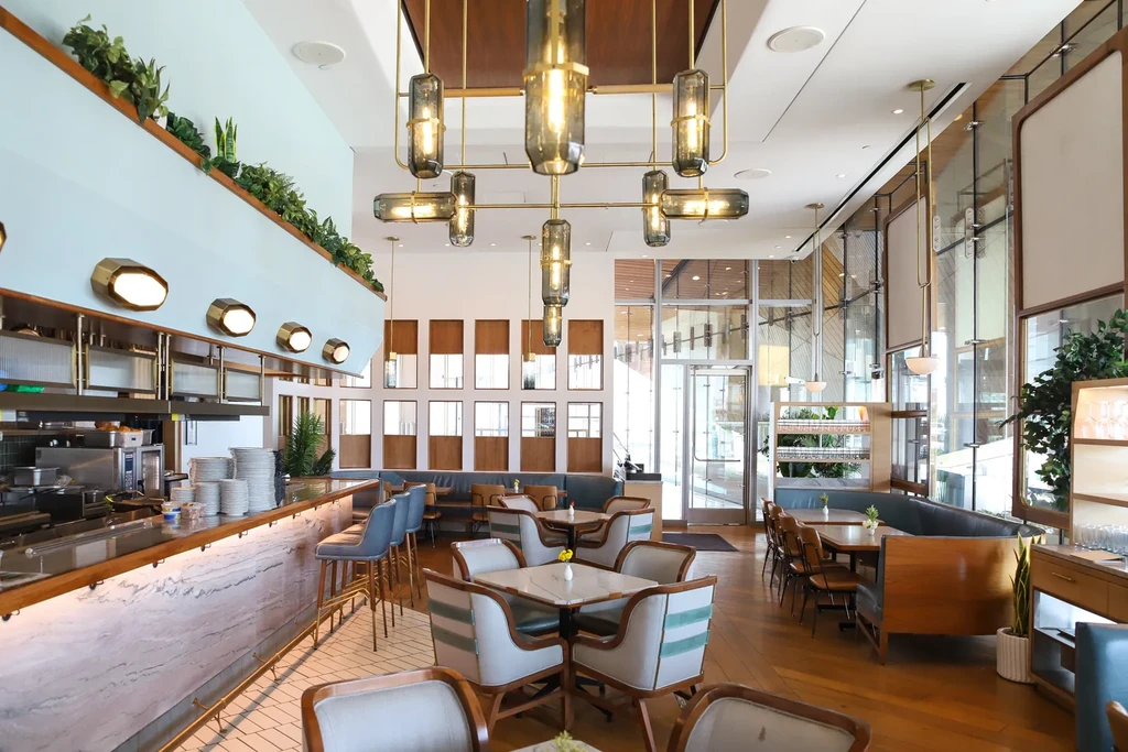 Bright, modern restaurant interior with blue bar stools and diverse seating.