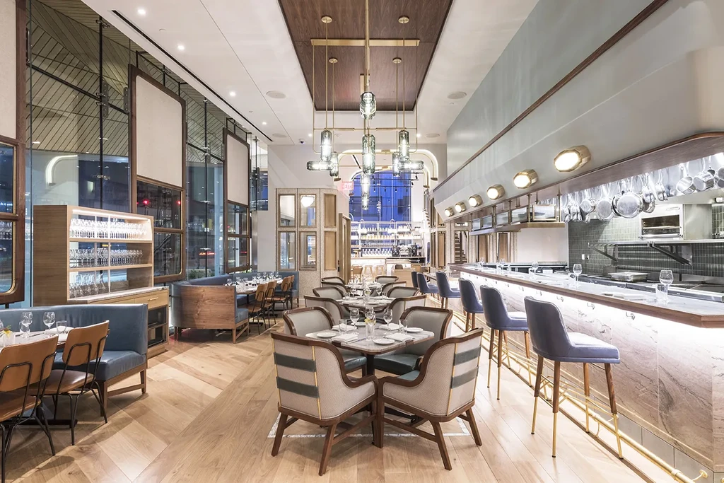 Modern, empty restaurant interior with dining tables, bar, and open kitchen.