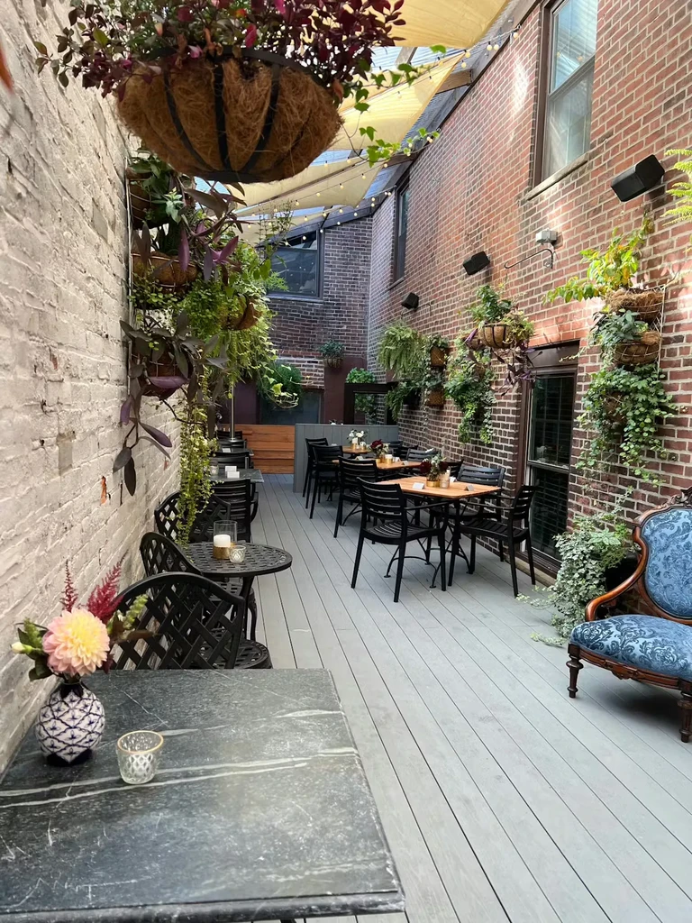 Lush outdoor dining patio with brick walls and string lights.