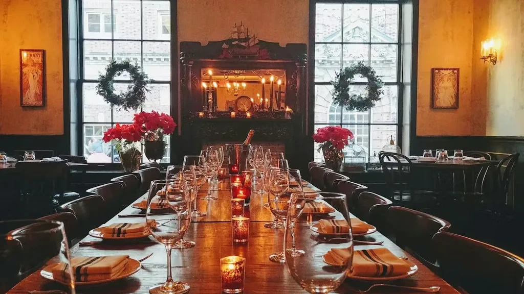 Elegant dining hall with a long table, festive decor, and fireplace.