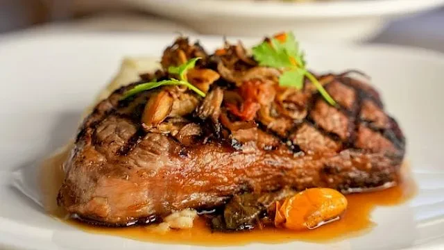 Thick grilled steak, topped with mushrooms, onions, herbs, and rich sauce.