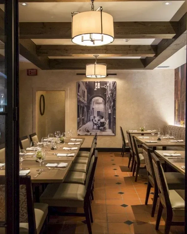 Restaurant dining room with set tables, terracotta floor, and exposed beams.