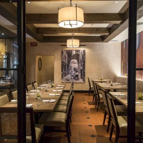 Restaurant interior with set tables, exposed beams, terracotta tiles, no people.