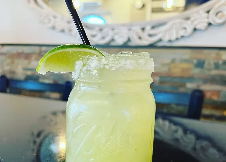 A frosty lime margarita in a mason jar with salt and lime.