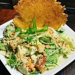 Close-up salad with creamy dressing, nuts, sesame, and a golden crisp.