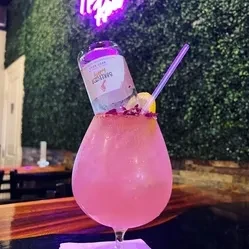 Pink cocktail with inverted mini bubbly bottle and lemon slice.