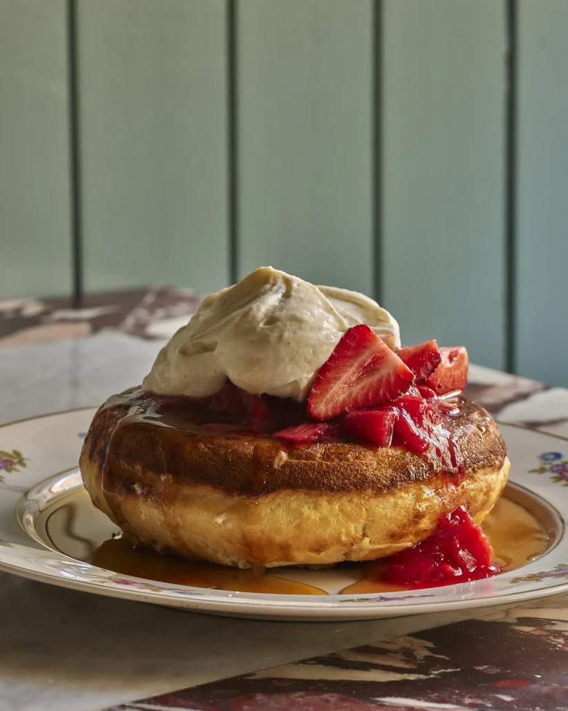 Thick golden pastry with amber syrup, whipped cream, and sliced strawberries.