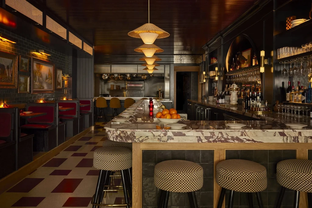 Elegant restaurant bar with marble counter, velvet booths, and checkerboard floor.