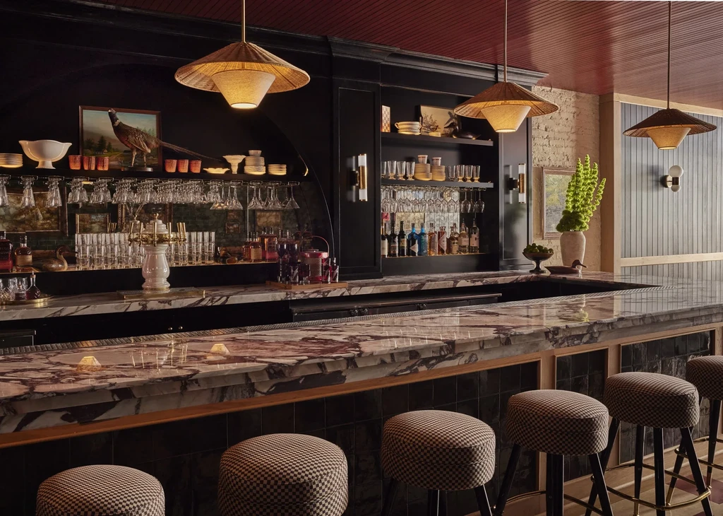 Dimly lit bar with marble counter, checkerboard stools, and extensive back bar.