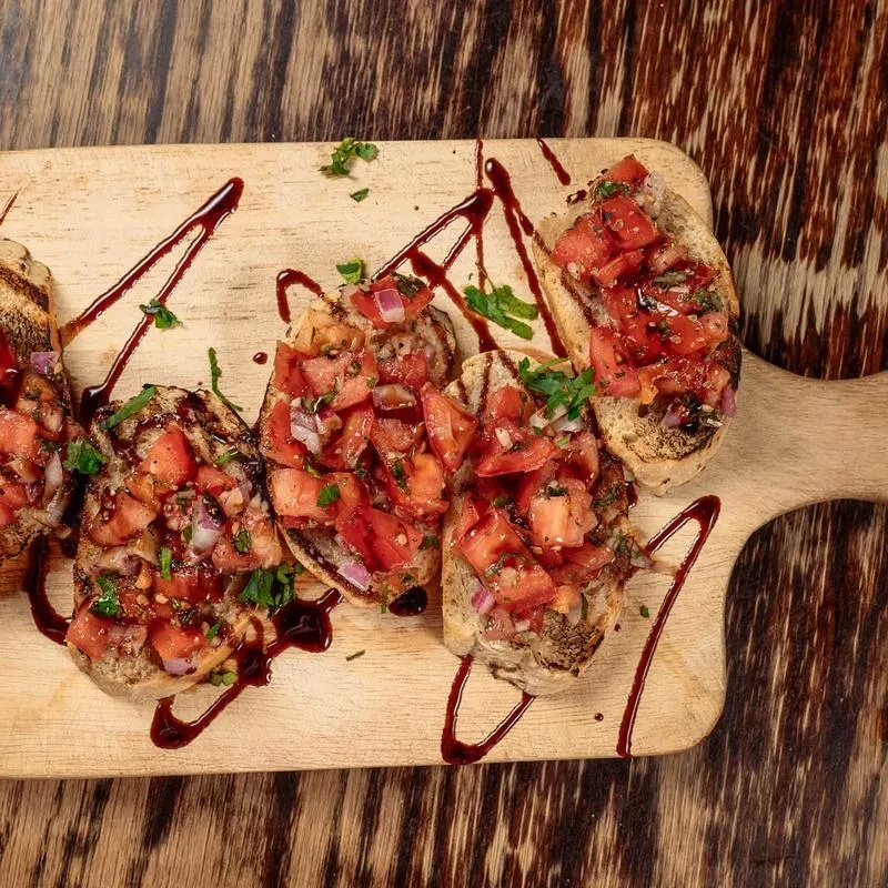 Overhead: Bruschetta with tomatoes, red onion, herbs, and balsamic glaze.