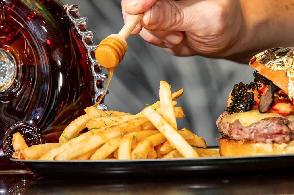 Luxurious burger with caviar, truffle, gold leaf, fries, and drizzled honey.