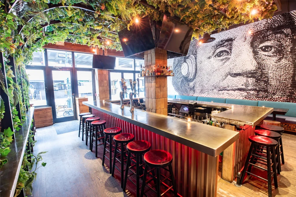 Vibrant bar with illuminated red counter, foliage ceiling, and Franklin mural.
