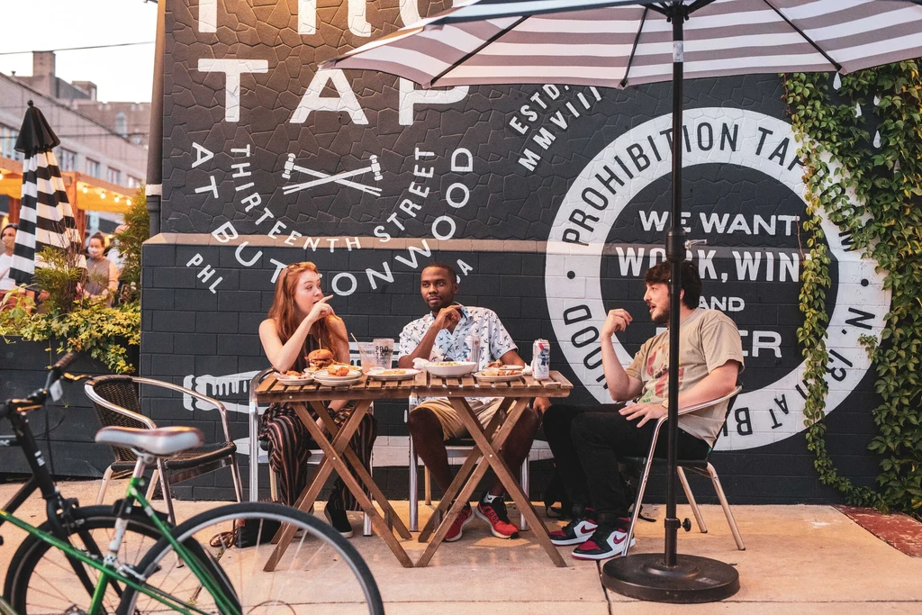 Three people eating burgers and drinks at The Tap.