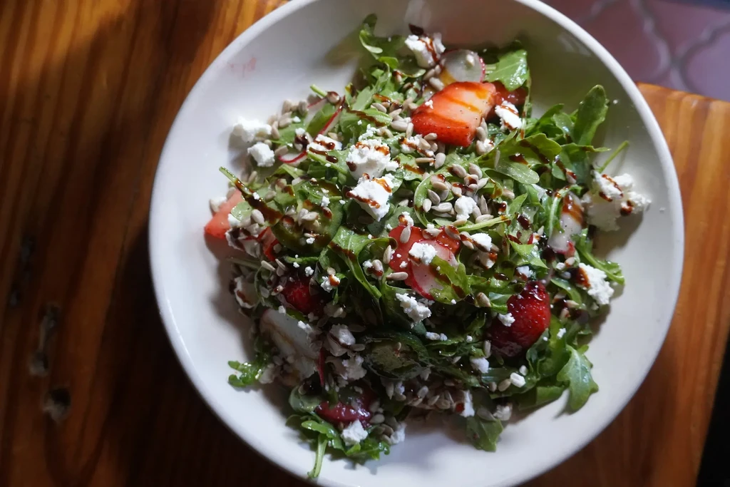 Arugula salad with strawberries, crumbled cheese, sunflower seeds, balsamic drizzle.