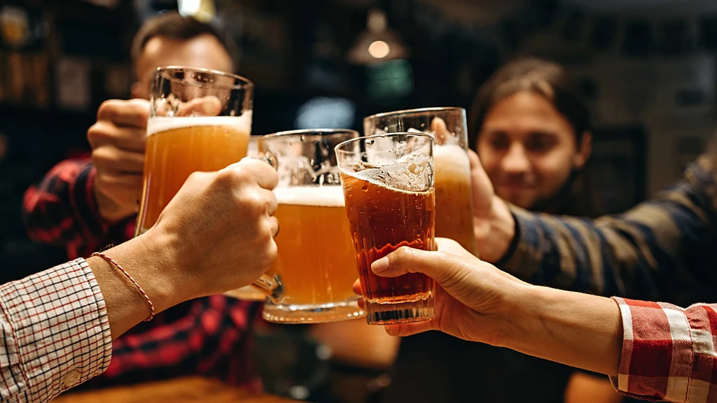 Close-up of four hands toasting with various beer glasses.