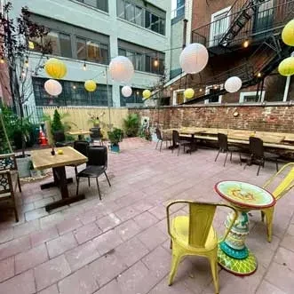 Urban outdoor patio with string lights, paper lanterns, and various seating.
