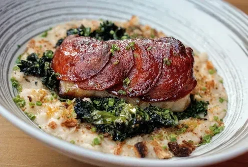 Plated dish: seared protein, chorizo, creamy puree, greens, and crunchy bits.